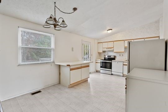 kitchen featuring appliances with stainless steel finishes, a chandelier, decorative light fixtures, and plenty of natural light