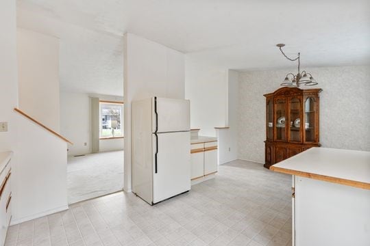 kitchen with pendant lighting, white cabinetry, a chandelier, and white refrigerator