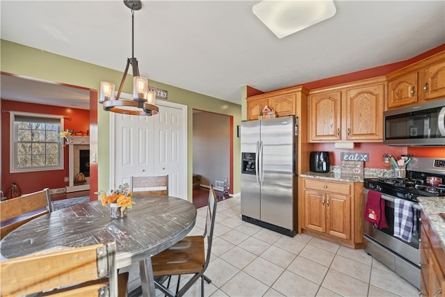 kitchen featuring pendant lighting, light stone countertops, a notable chandelier, light tile patterned flooring, and stainless steel appliances