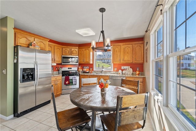 kitchen with an inviting chandelier, sink, hanging light fixtures, light tile patterned floors, and appliances with stainless steel finishes