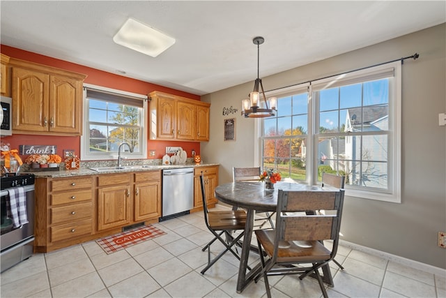 kitchen with light stone countertops, appliances with stainless steel finishes, sink, decorative light fixtures, and light tile patterned flooring