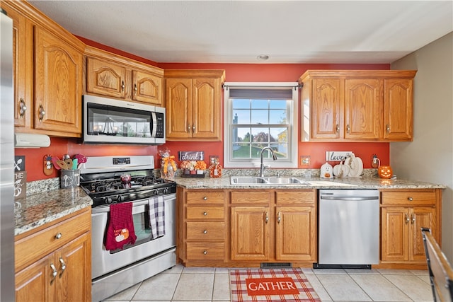 kitchen featuring light tile patterned flooring, sink, light stone countertops, and stainless steel appliances