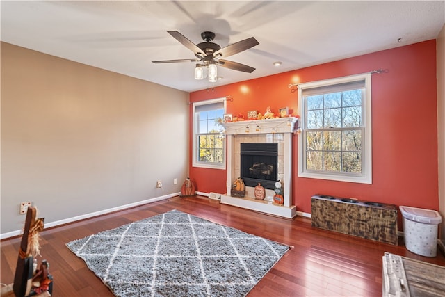 living room featuring a tile fireplace, ceiling fan, plenty of natural light, and hardwood / wood-style floors