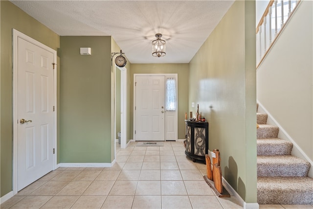 foyer entrance with light tile patterned floors and a textured ceiling