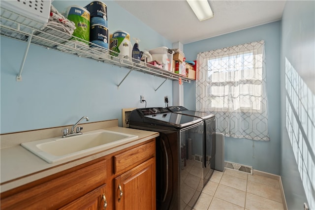 laundry area featuring cabinets, light tile patterned flooring, washing machine and dryer, and sink