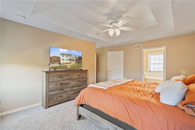 carpeted bedroom with a raised ceiling, connected bathroom, ceiling fan, and a textured ceiling