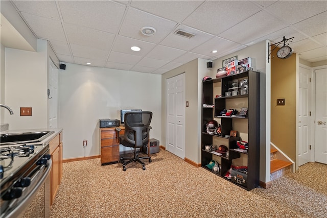 carpeted office with a paneled ceiling and sink