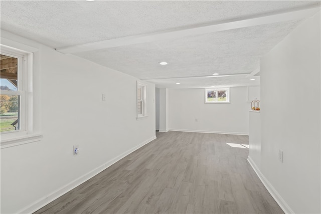 spare room with a healthy amount of sunlight, a textured ceiling, and light hardwood / wood-style flooring