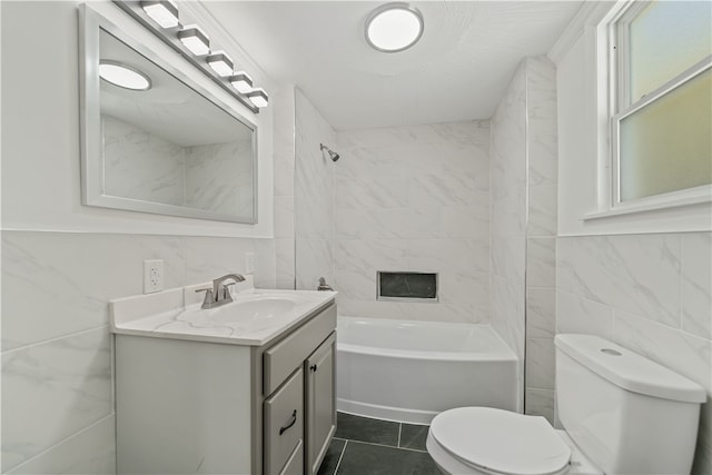 full bathroom with toilet, tile patterned floors, tile walls, tiled shower / bath, and vanity