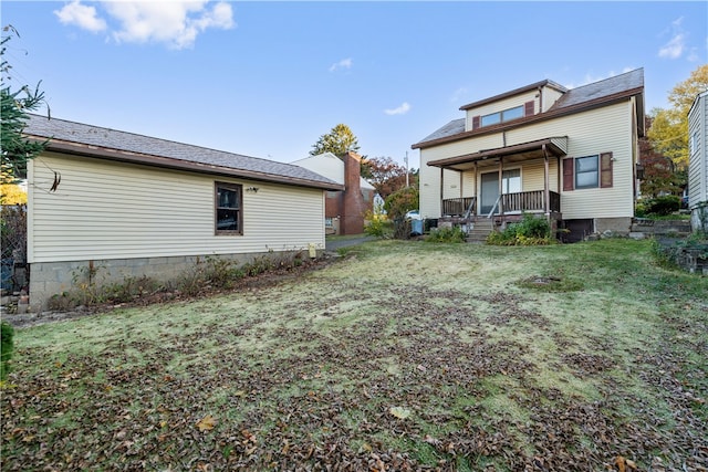 rear view of property featuring a lawn and a porch