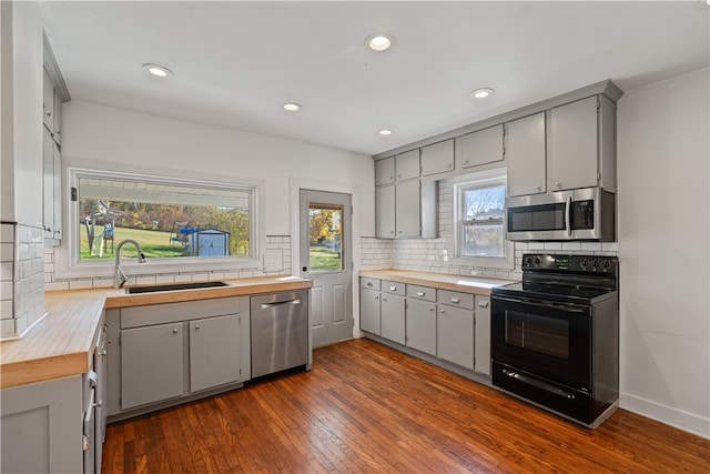 kitchen with gray cabinets, dark wood-type flooring, stainless steel appliances, and sink