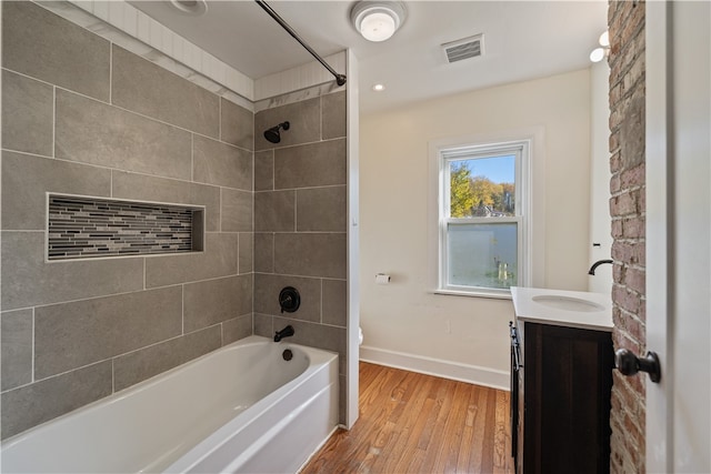 full bathroom featuring tiled shower / bath, vanity, wood-type flooring, and toilet