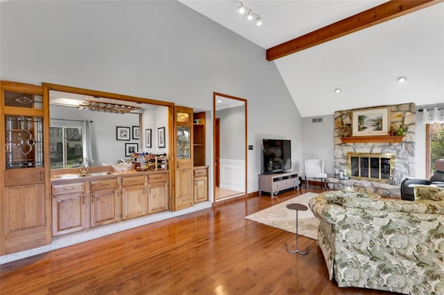 living room featuring beam ceiling, high vaulted ceiling, wood-type flooring, and a fireplace