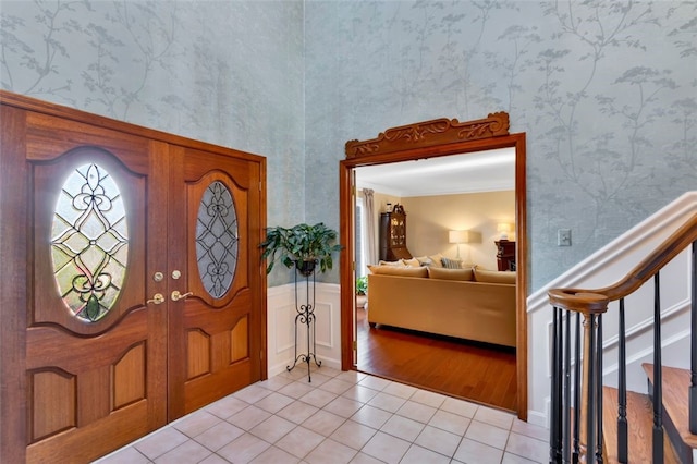 entrance foyer with french doors, crown molding, and light wood-type flooring