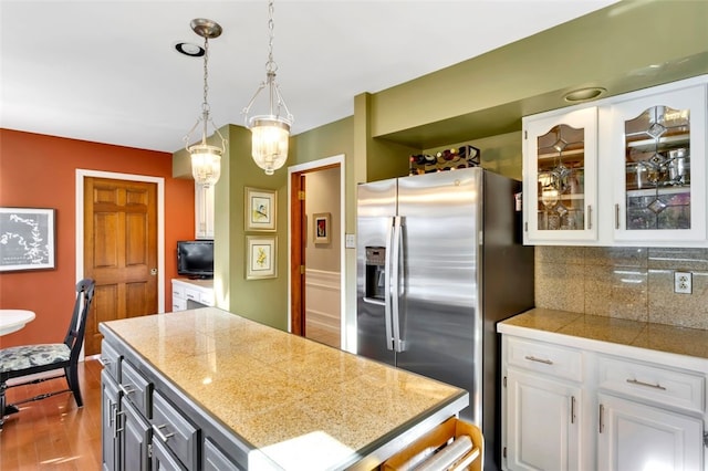 kitchen with decorative backsplash, white cabinets, dark wood-type flooring, pendant lighting, and stainless steel refrigerator with ice dispenser