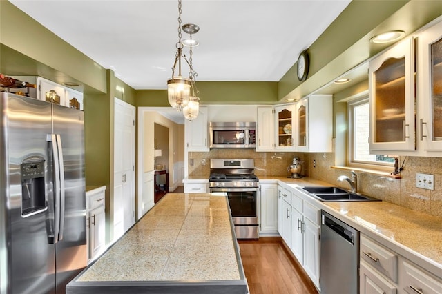 kitchen with a center island, appliances with stainless steel finishes, pendant lighting, and white cabinets