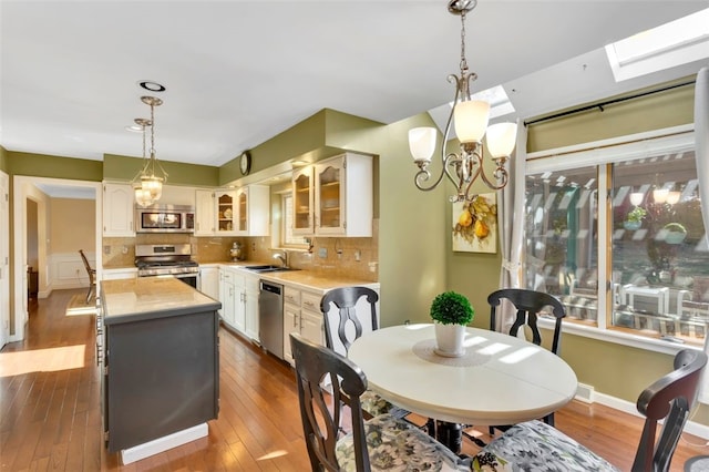 dining room featuring sink, dark wood-type flooring, and a skylight