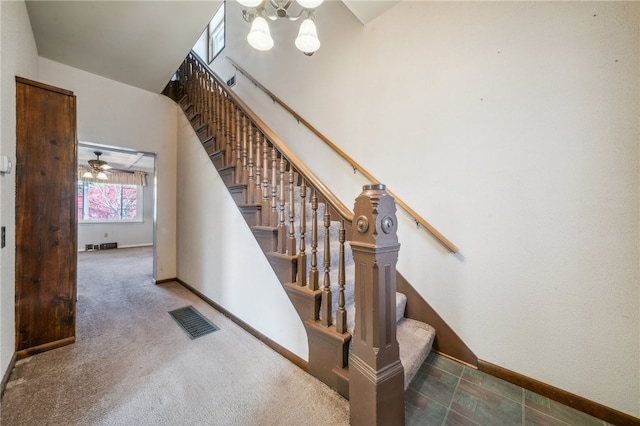 stairway with ceiling fan, carpet floors, and a high ceiling