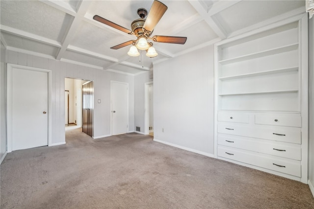 unfurnished bedroom with beam ceiling, coffered ceiling, light carpet, and ceiling fan