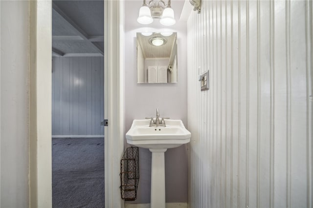 bathroom featuring beamed ceiling and wood walls