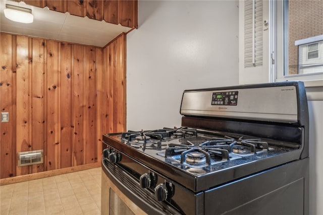 kitchen featuring gas stove and wood walls