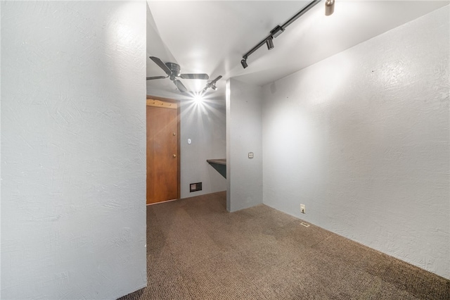 empty room with carpet floors, rail lighting, and ceiling fan