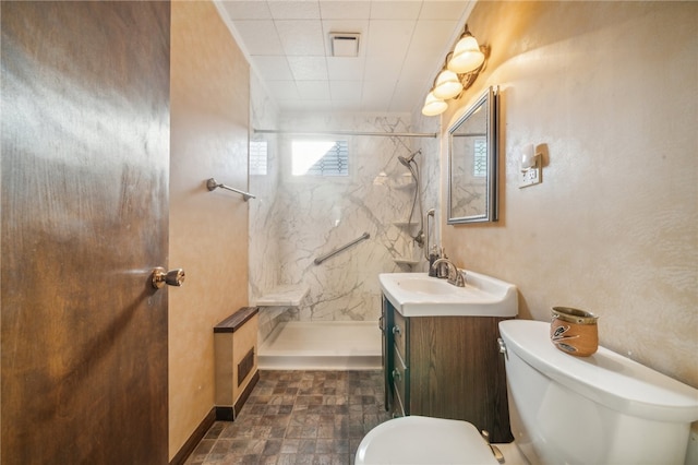 bathroom with a tile shower, toilet, and vanity