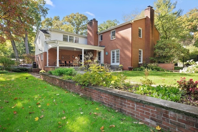 back of house with a patio and a lawn