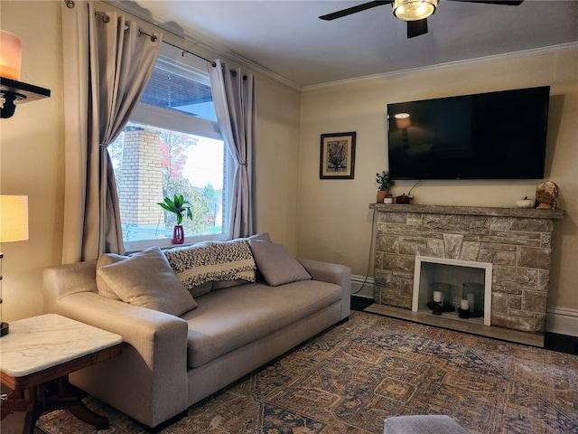 living room with ornamental molding, a stone fireplace, and ceiling fan