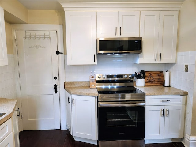 kitchen with backsplash, dark wood-type flooring, appliances with stainless steel finishes, and white cabinets