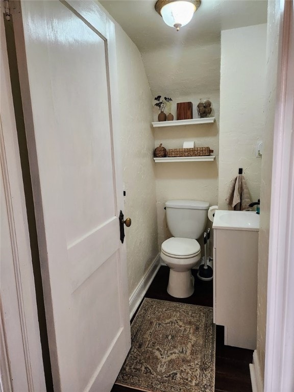 bathroom featuring vanity, hardwood / wood-style floors, vaulted ceiling, and toilet