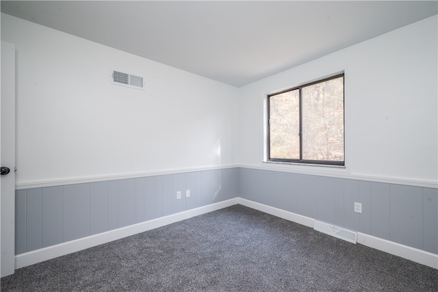 unfurnished room featuring dark colored carpet