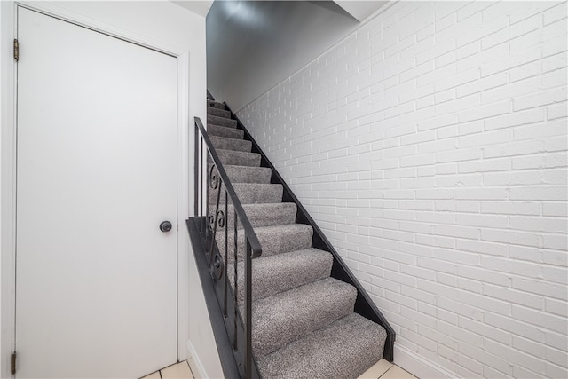 stairs with brick wall and tile patterned flooring