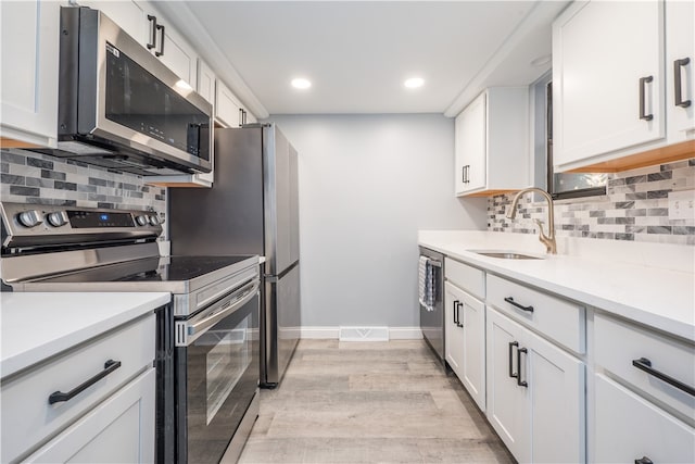 kitchen featuring sink, backsplash, light hardwood / wood-style floors, stainless steel appliances, and white cabinets