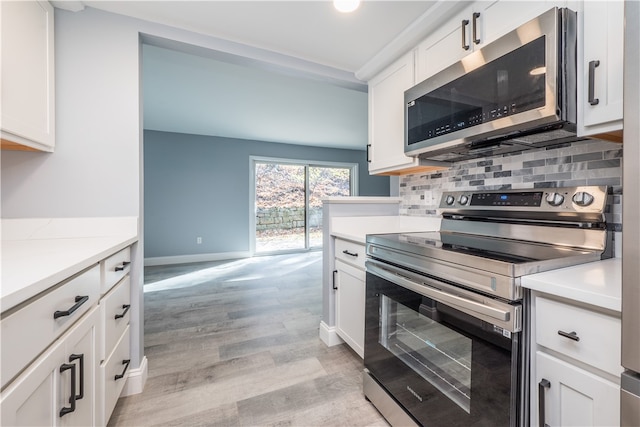 kitchen with light hardwood / wood-style floors, stainless steel appliances, tasteful backsplash, and white cabinets