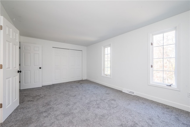 unfurnished bedroom with multiple windows, a closet, and carpet flooring