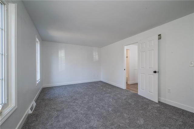 spare room featuring dark carpet