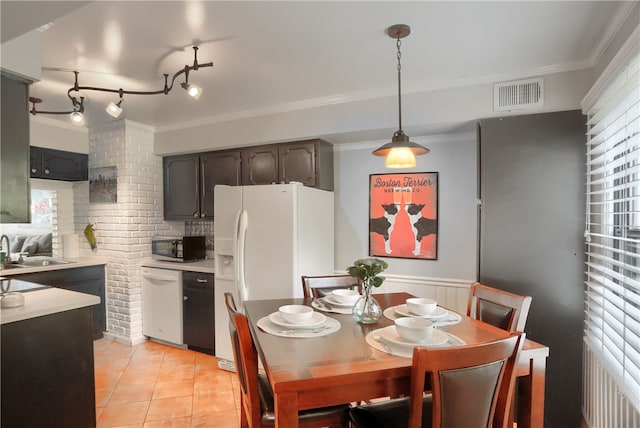 dining room with crown molding, sink, and light tile patterned floors