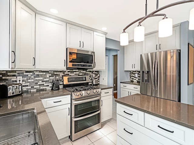 kitchen featuring backsplash, white cabinets, hanging light fixtures, light tile patterned floors, and stainless steel appliances