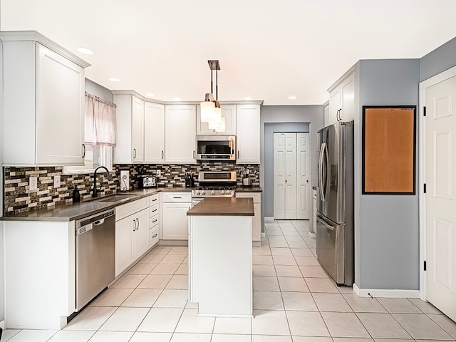 kitchen with sink, decorative light fixtures, a kitchen island, white cabinetry, and stainless steel appliances