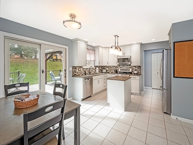 kitchen with sink, hanging light fixtures, decorative backsplash, light tile patterned floors, and appliances with stainless steel finishes