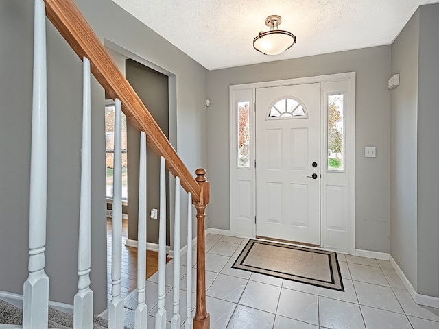 tiled entryway with a textured ceiling