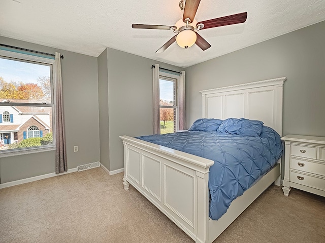 carpeted bedroom featuring a textured ceiling and ceiling fan