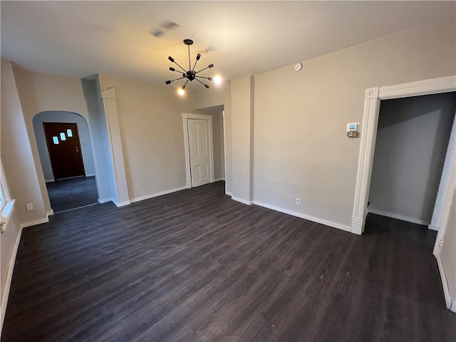 unfurnished living room featuring dark hardwood / wood-style flooring and an inviting chandelier