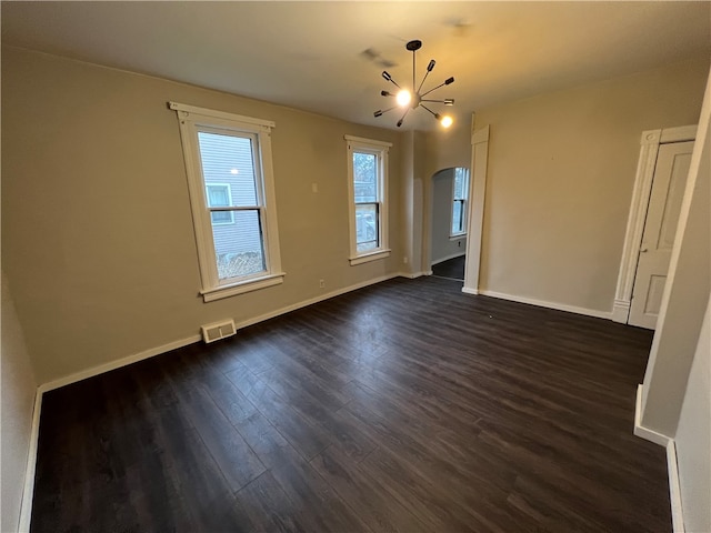 empty room featuring an inviting chandelier and dark hardwood / wood-style flooring