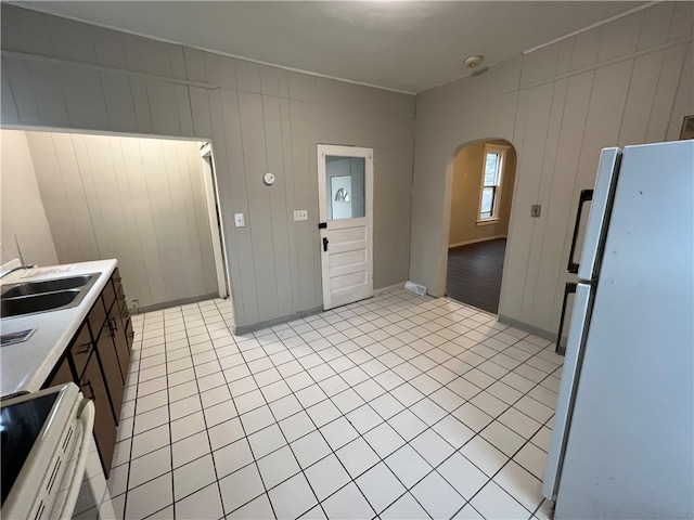 kitchen with stove, sink, light tile patterned floors, and white refrigerator