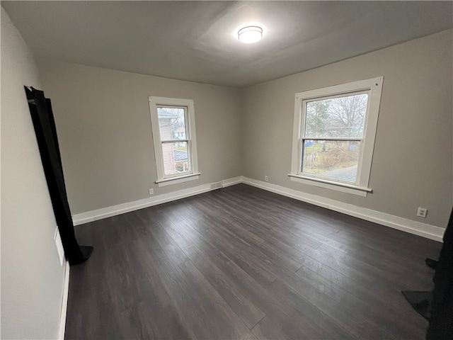 spare room featuring dark wood-type flooring and a healthy amount of sunlight