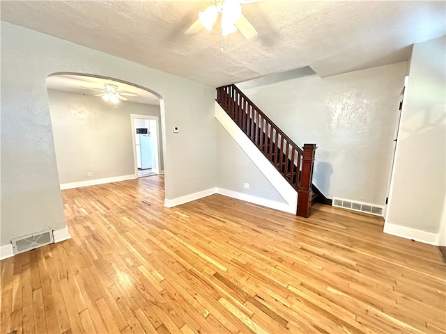 unfurnished living room with light hardwood / wood-style flooring, a textured ceiling, and ceiling fan