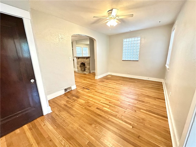 spare room featuring a fireplace, light hardwood / wood-style floors, and ceiling fan