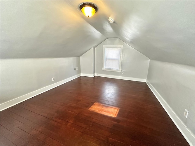 additional living space featuring vaulted ceiling and dark hardwood / wood-style flooring